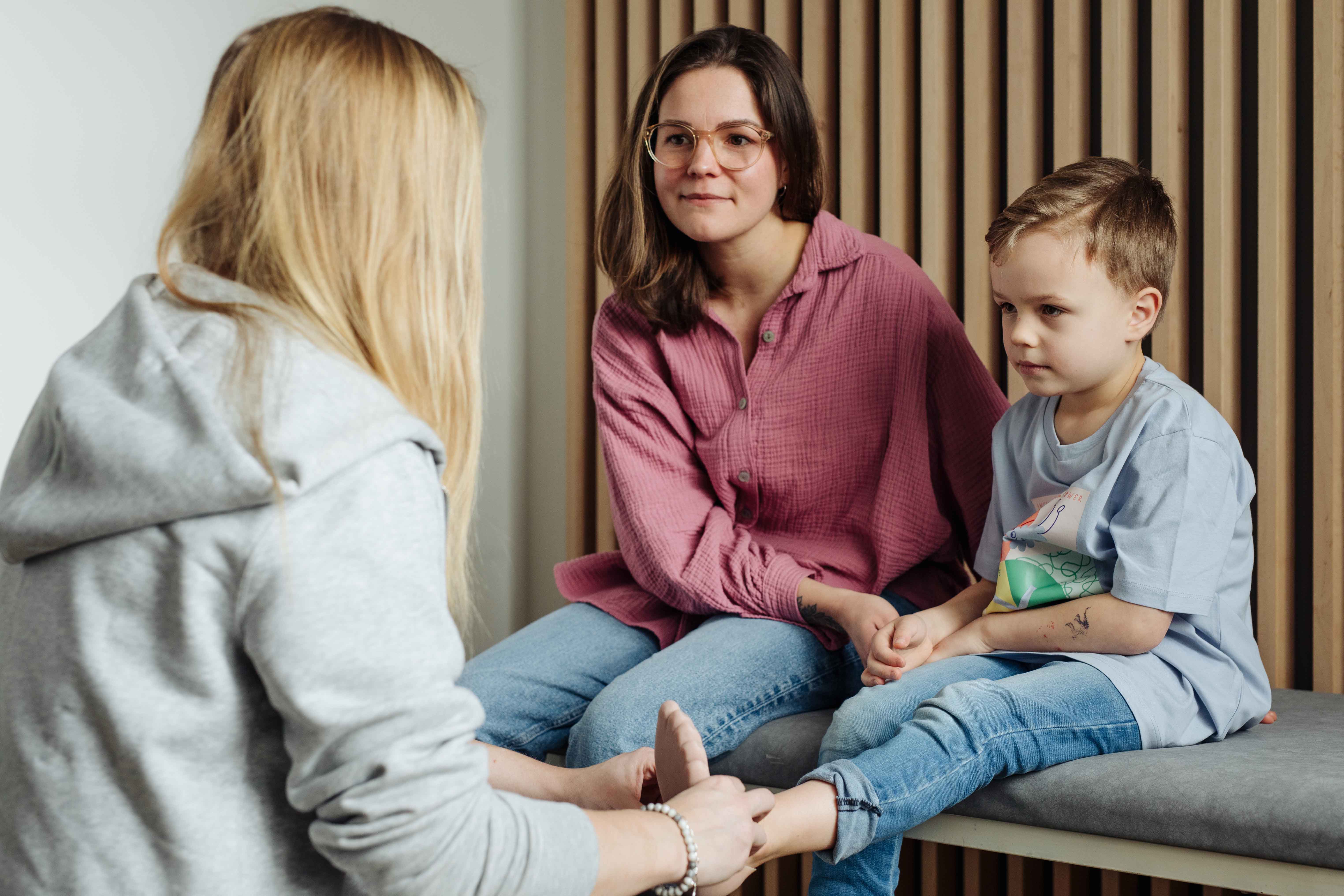 Kathrin von Hodey Kids &uuml;berpr&uuml;ft den Sitz der Fu&szlig;prothese eines kleinen jungen, der mit seiner Mutter auf einer Liege Platz genommen hat.